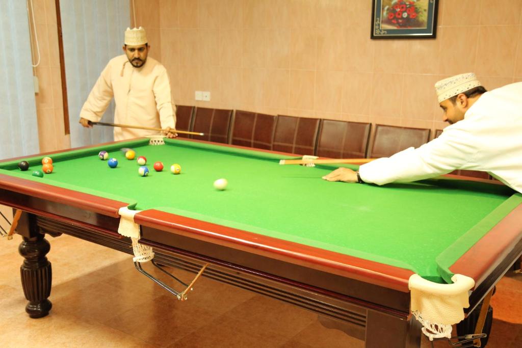 dos hombres jugando al billar en Shorfet Al Alamin Hotel en Al Ḩamrāʼ