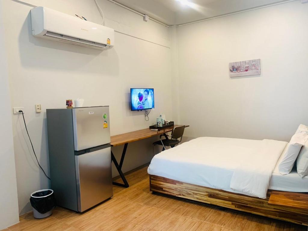 a room with a bed and a desk and a refrigerator at โรงแรมควีนส์ (Queen) in Ban Tha Kham