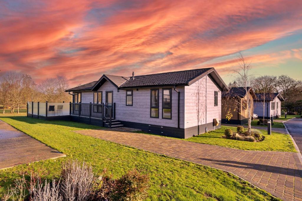 a small house on a lawn with a sunset at Finest Retreats - Pembroke Luxury Lodge in Bourn