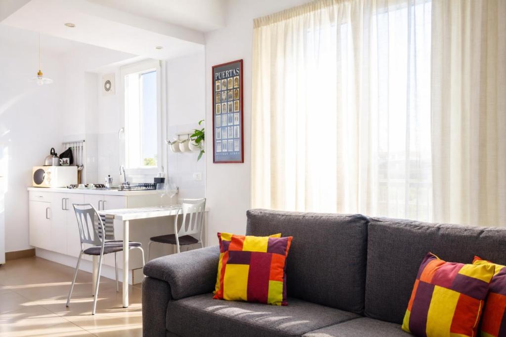 a living room with a gray couch and a kitchen at Cuore Flat in Modica