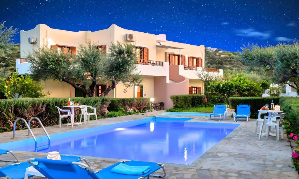 a villa with a swimming pool at night at Plaisir Beachside Apts in Agios Nikolaos