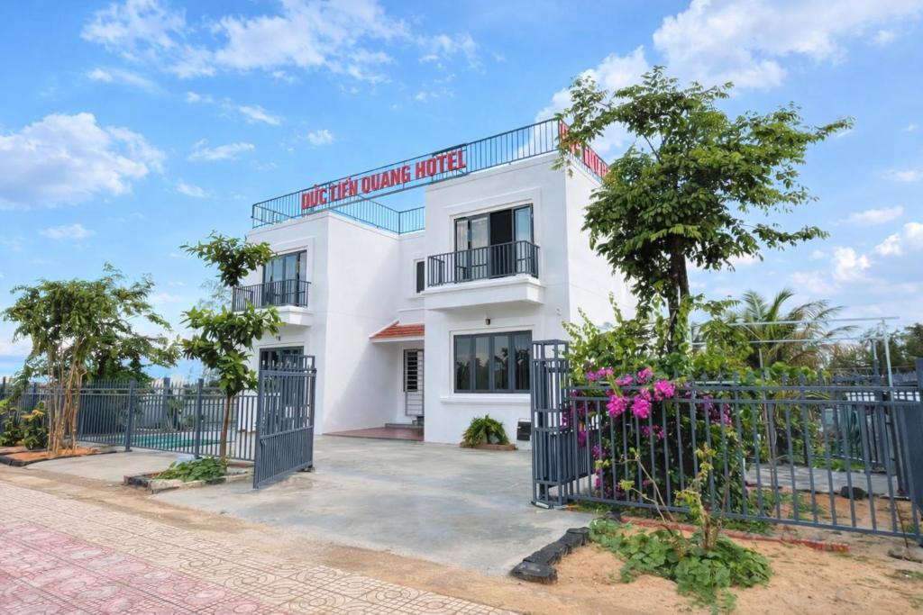 a white building with a gate and a fence at Đức Lưu Quang Hotel Bình Thuận in Tuy Phong