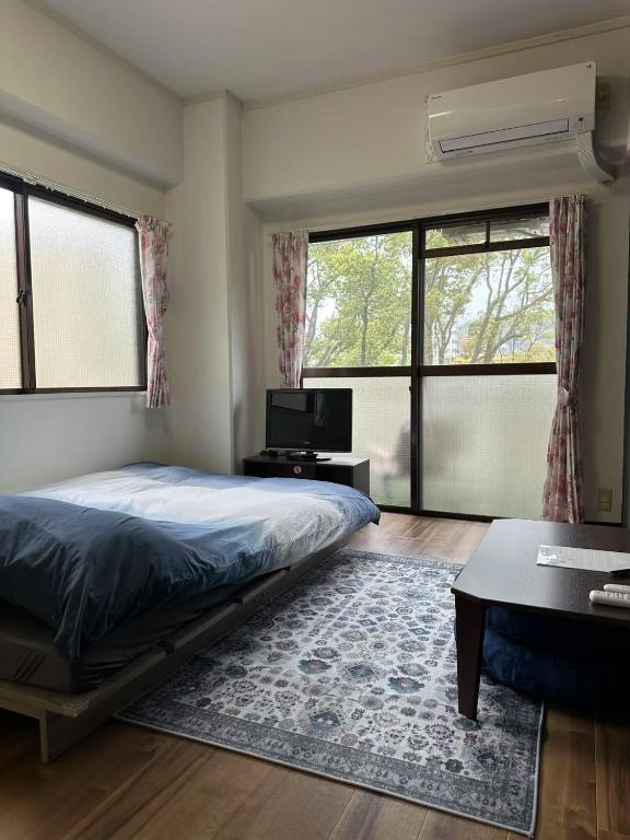 a bedroom with a bed and a tv and windows at Peace Wing 3C in Hiroshima