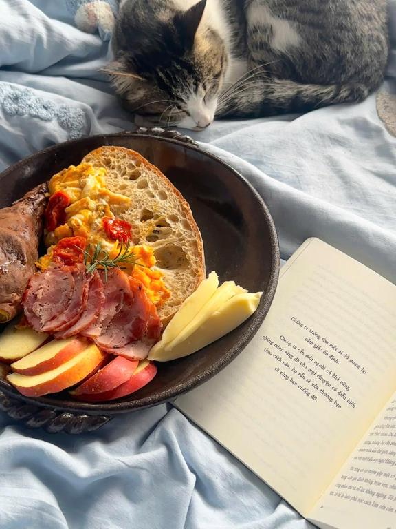 a plate of food with meat and bread and a cat at The Hermit Sapa Homestay in Sa Pả