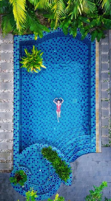 a person with an umbrella in a swimming pool at Kraam Silhouette Hotel and Cafe Phuket- Chalong pier Hotel in Chalong