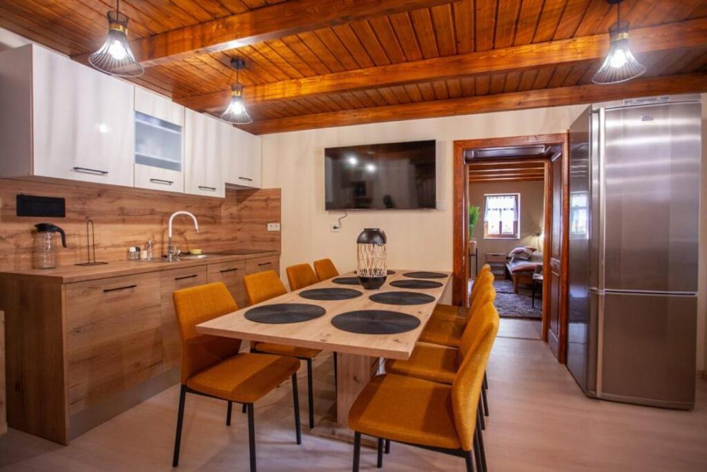 a kitchen with a table with chairs and a refrigerator at Nagyon Vadon vendégház in Háromhuta