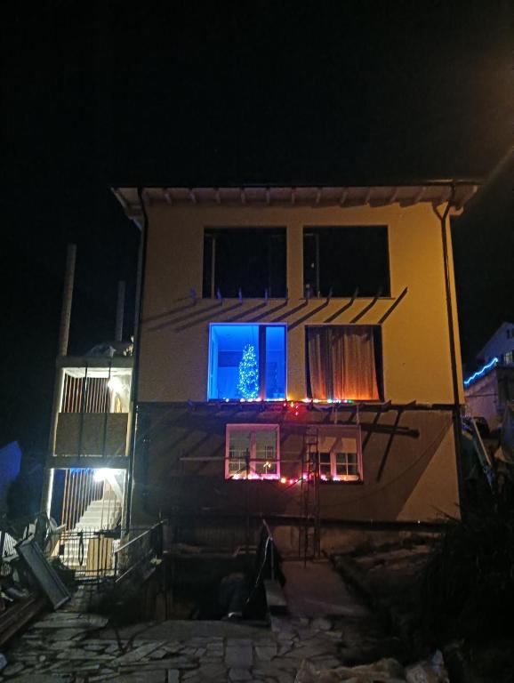 a house with a christmas tree in the window at night at B&B Sentiero Rusca in Sondrio