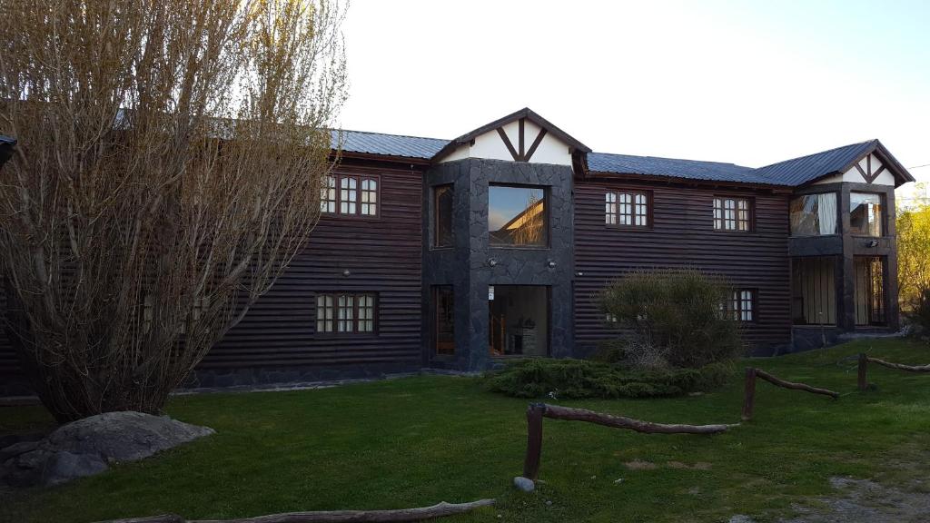 a large wooden house with a tree in front of it at Hosteria Vientos Del Sur in El Calafate