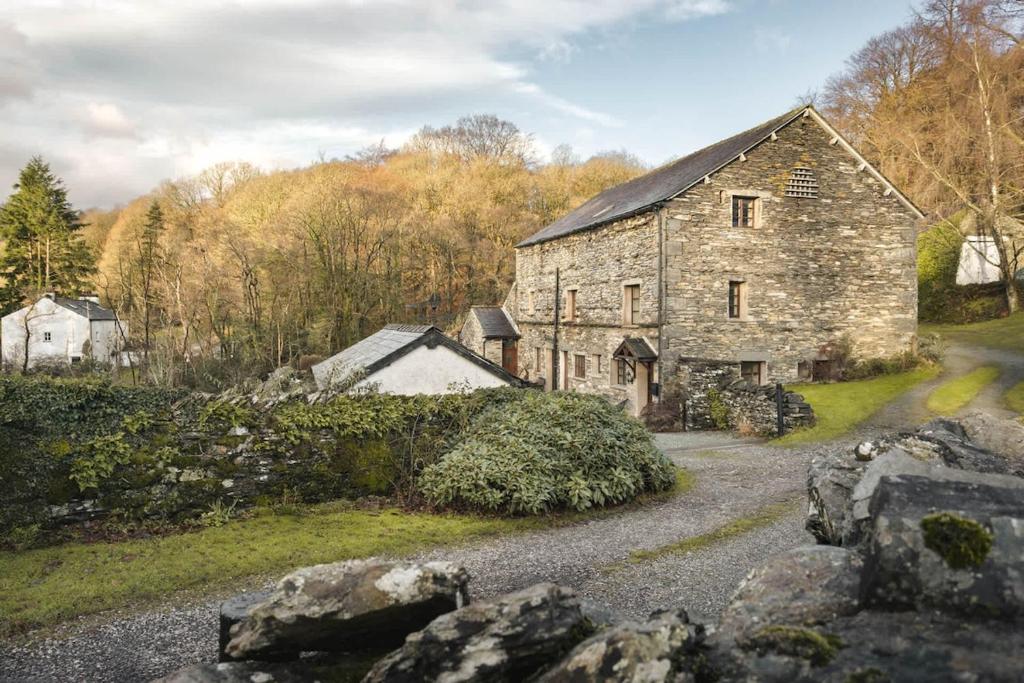 an old stone house on a hill with a road at 1 Force Mill Barn - Ridgestone in Ulverston