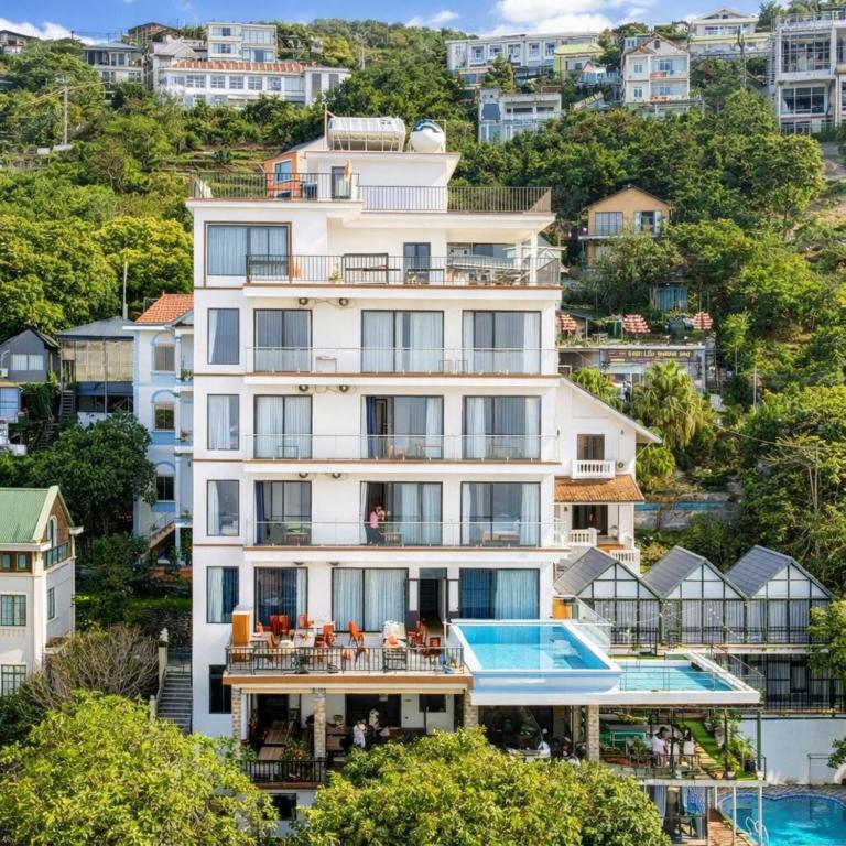 an apartment building with a swimming pool in front of a city at Daisy Hotel Tam Dao in Tam Ðảo