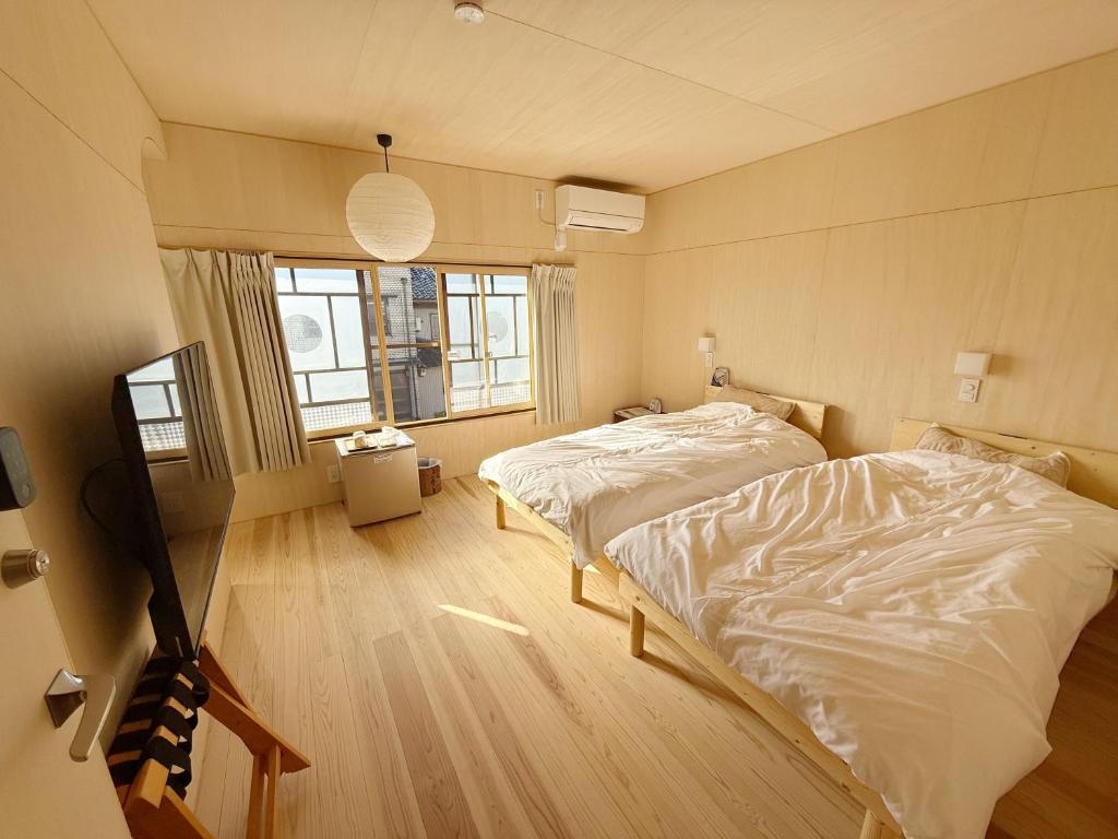 a bedroom with two beds and a window at なごらーれ放生津屋 in Shimminato