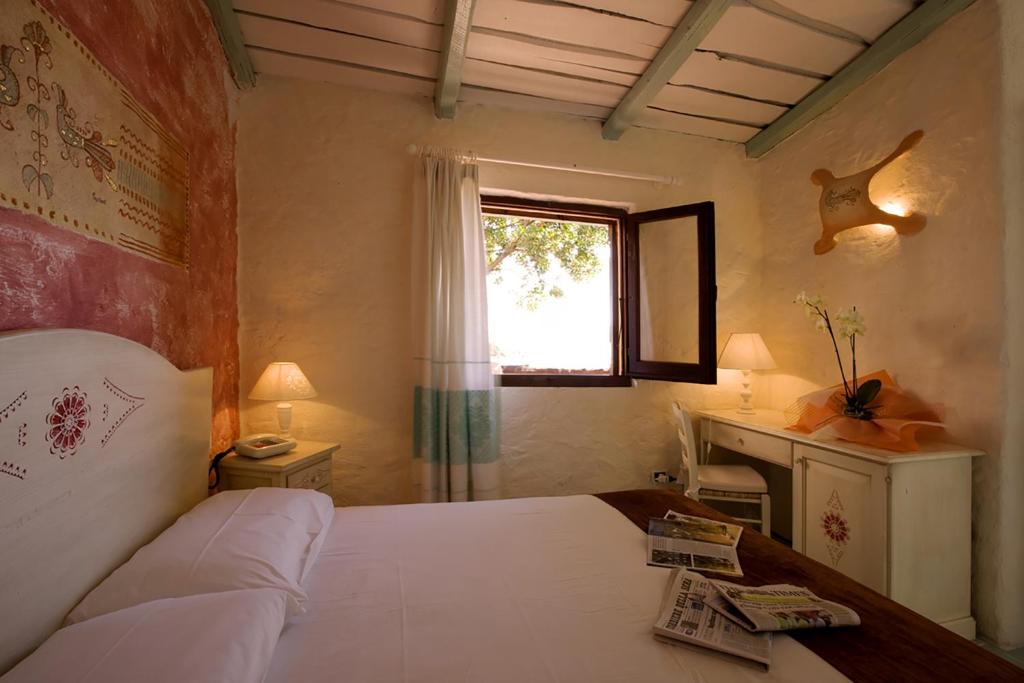 a bedroom with a bed and a desk and a window at Hotel Don Diego in Porto San Paolo
