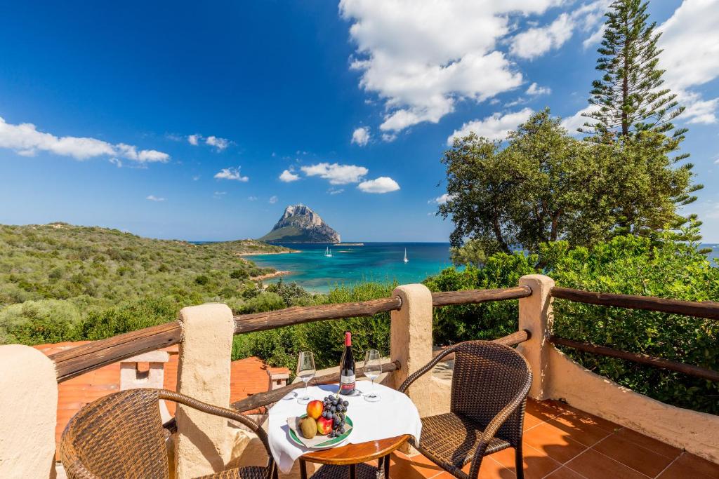 a table and chairs on a deck with a view of the ocean at Hotel Don Diego in Porto San Paolo