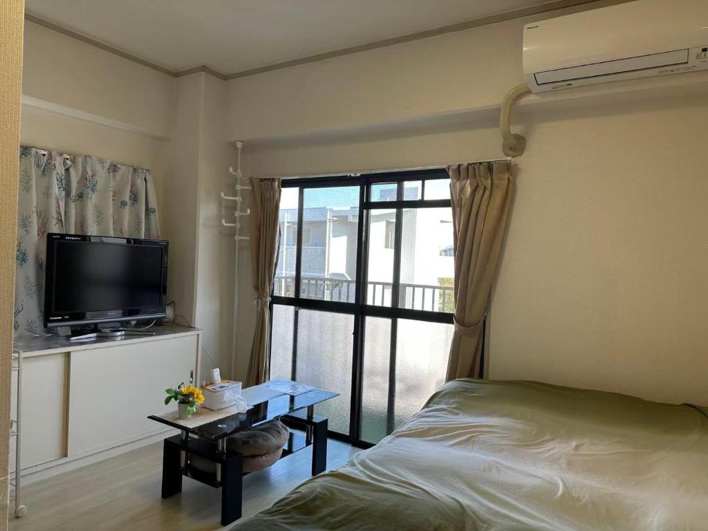 a bedroom with a bed and a tv and a table at Peace Wing 5A in Kami-nagarekawachō