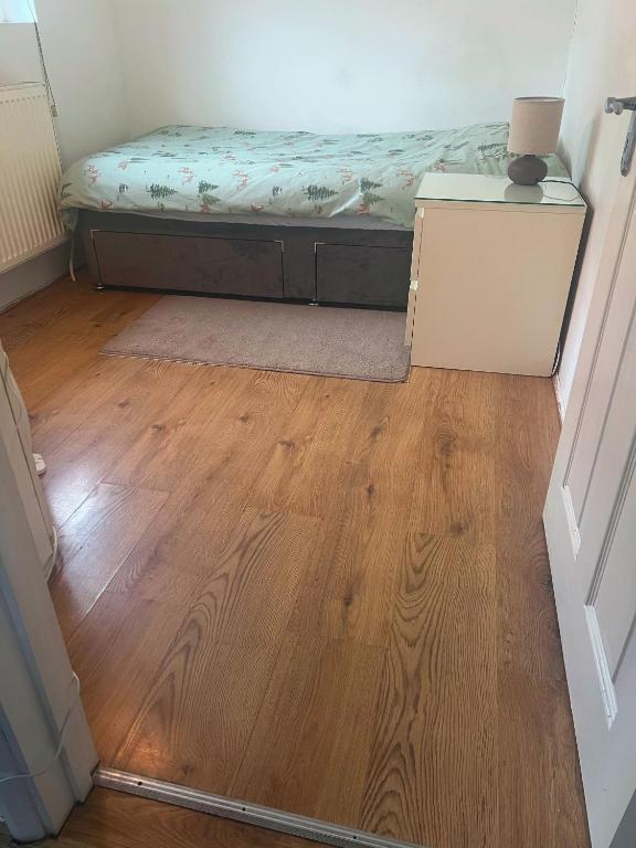 a bedroom with a bed and a wooden floor at Compact single room A near Heathrow with 24 hour buses to all terminals in Feltham