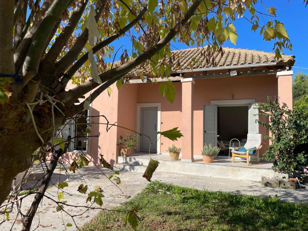 a small pink house with a chair in front of it at Papiri Beach Summerhouse in Agios Georgios