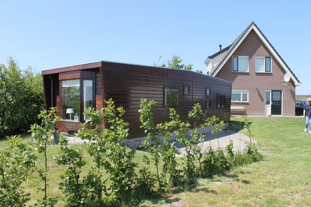 a wooden house in a yard next to a house at Wendy in Julianadorp