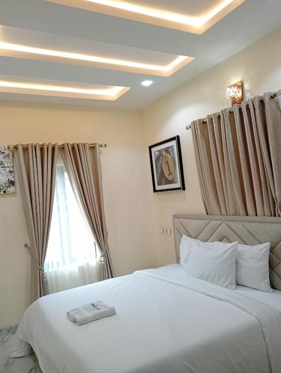 a bedroom with a large white bed and a window at Pinefield Courts Apartment in Akure