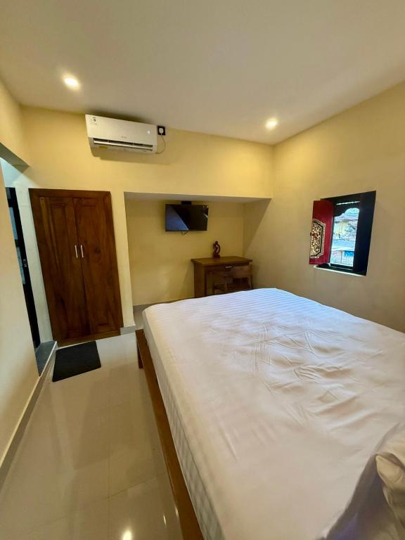 a bedroom with a large white bed and a air conditioner at Alena in Nusa Dua