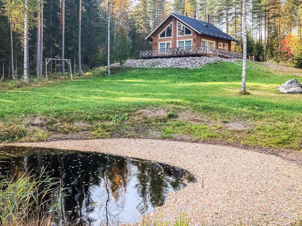 a house on a hill next to a pond at Holiday Home Inkeri by Interhome in Holiseva