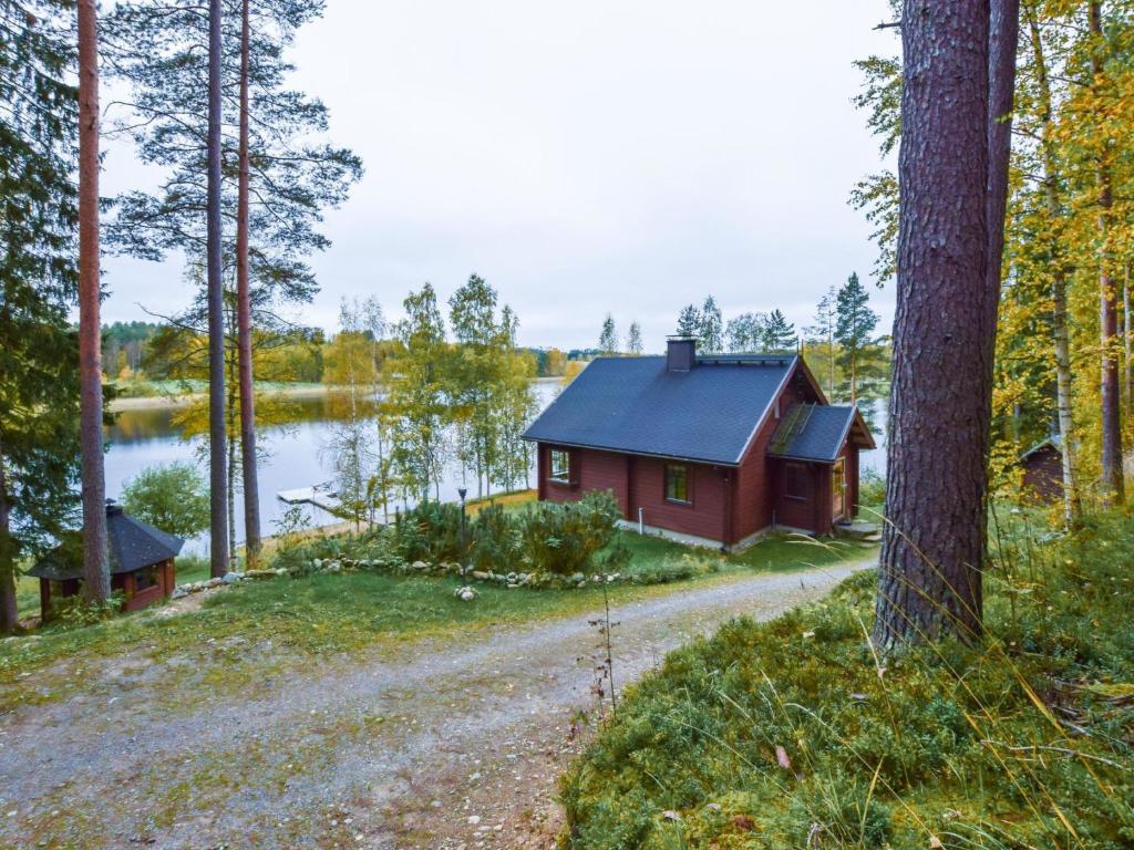 a red cabin in the woods next to a lake at Holiday Home Vuorimaja by Interhome in Kylänlahti