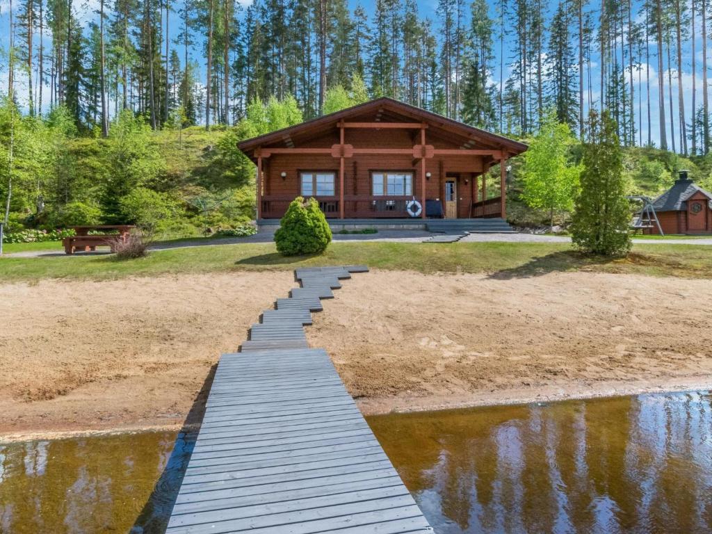 a log home with a wooden walkway leading to a pond at Holiday Home 7734 by Interhome in Kaartilankoski