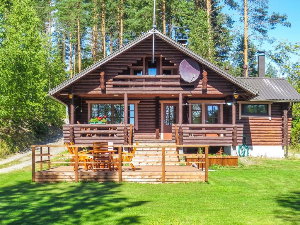 a log cabin with tables and chairs in front of it at Holiday Home Rantalaukka by Interhome in Haapiala