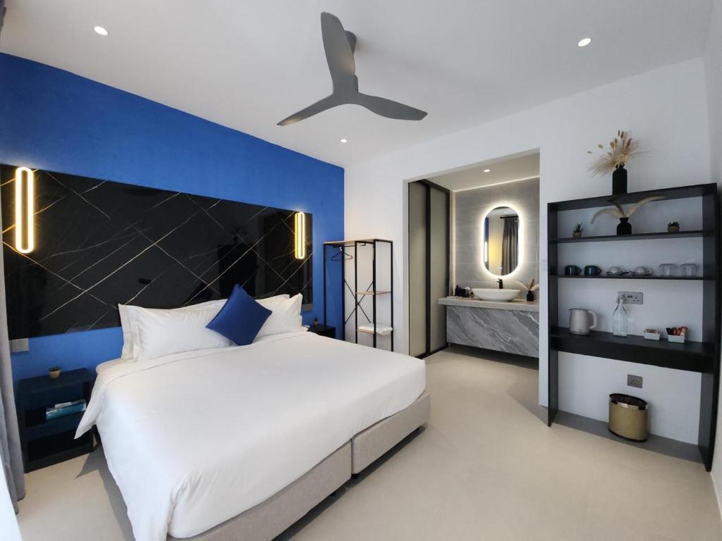 a bedroom with a large white bed and a blue wall at Velaa Dhigurah in Dhigurah