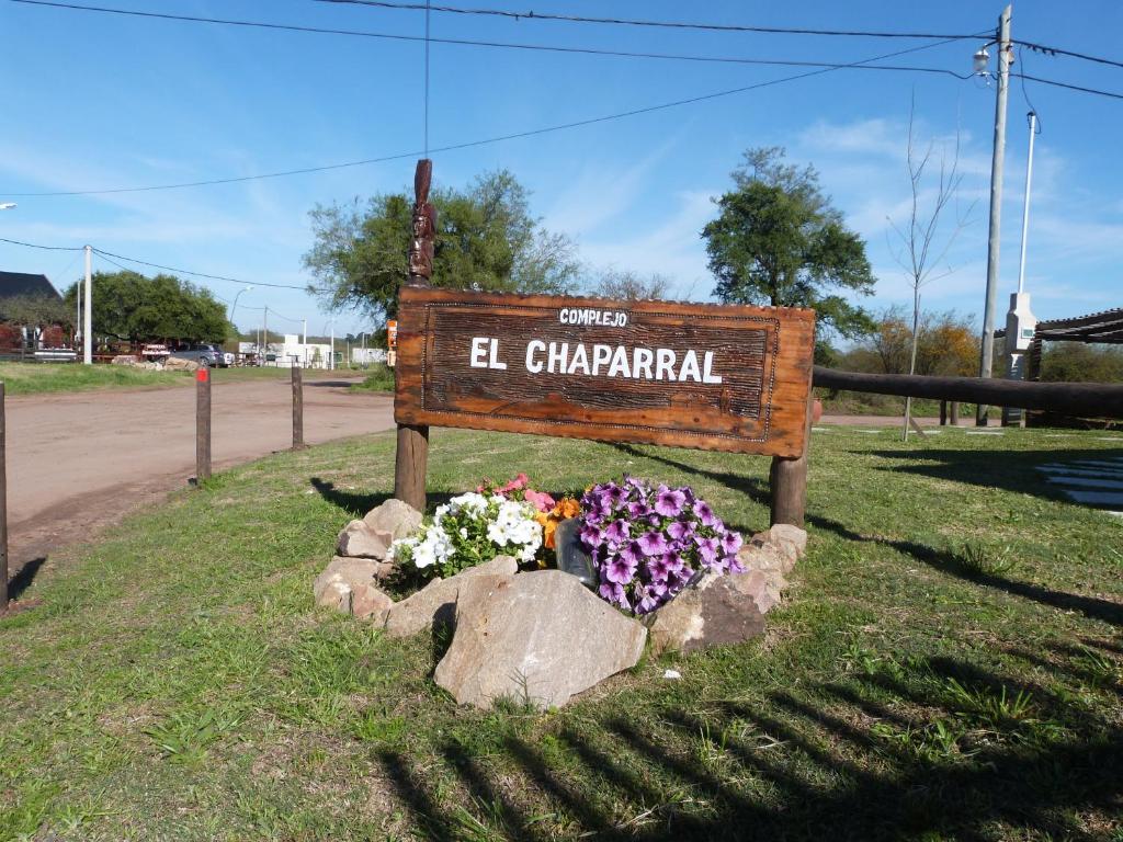 a sign for el chaparral with flowers in a rock at Complejo El Chaparral in Colón