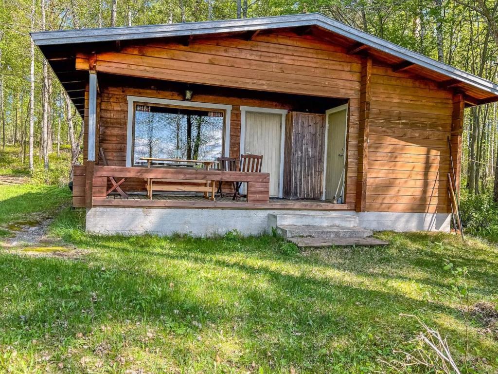 a wooden cabin with a bench and a table at Holiday Home Kuusiranta by Interhome in Harjula