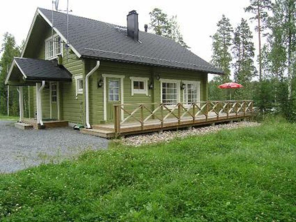 a small green house with a wooden fence at Holiday Home Villa helmi by Interhome in Holiseva
