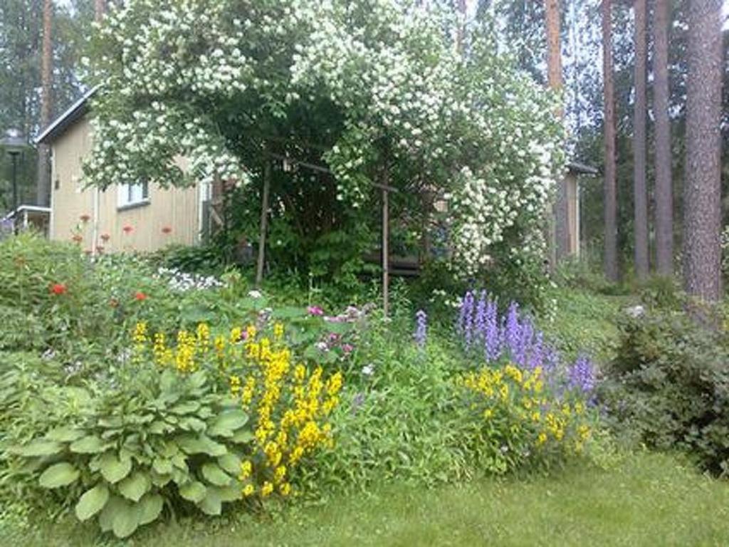 a garden with a bunch of flowers and a tree at Holiday Home Simola by Interhome in Nimimäki