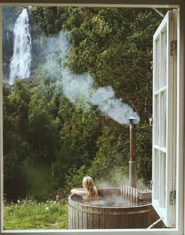a woman sitting in a hot tub in front of a waterfall at Waterfall Retreat in Kolo