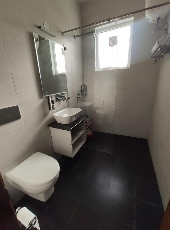 a bathroom with a toilet and a sink and a window at Surwel Hotel and Resort in Mussoorie