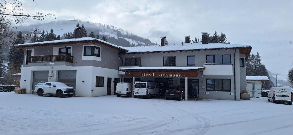 a building with vehicles parked outside of it in the snow at Ferienwohnungen Bachmann in Strassen