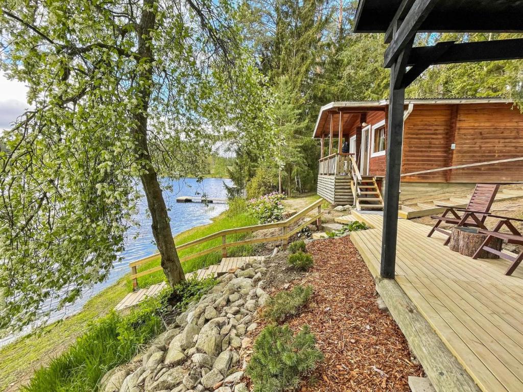 a cabin with a deck next to a body of water at Holiday Home Hellinki by Interhome in Vaskivesi