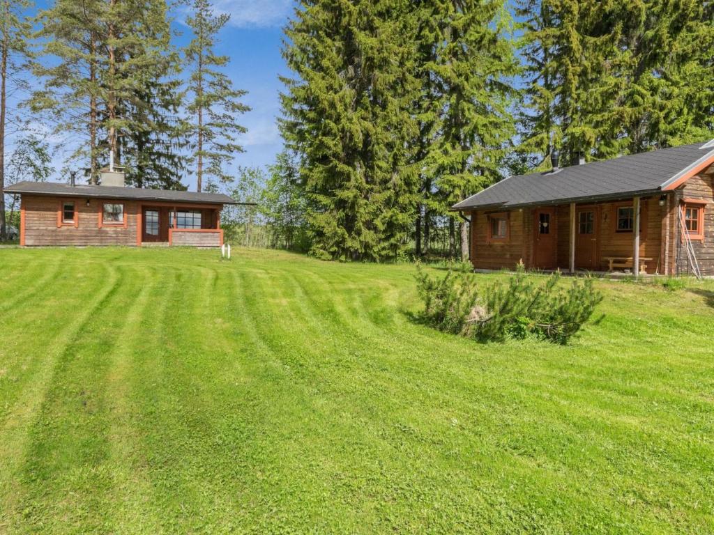 a log cabin with a large grass field in front of a house at Holiday Home Kasilahti by Interhome in Kilvakkala