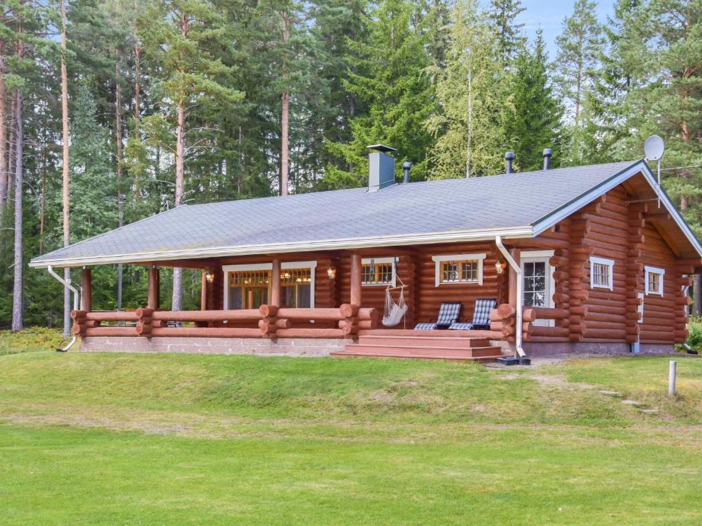 a log cabin in the woods with a porch at Holiday Home Kivitasku by Interhome in Kallionkieli