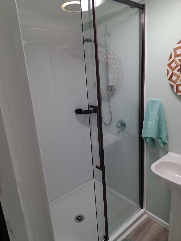 a shower with a glass door in a bathroom at Coro Coast getaway in Te Puru