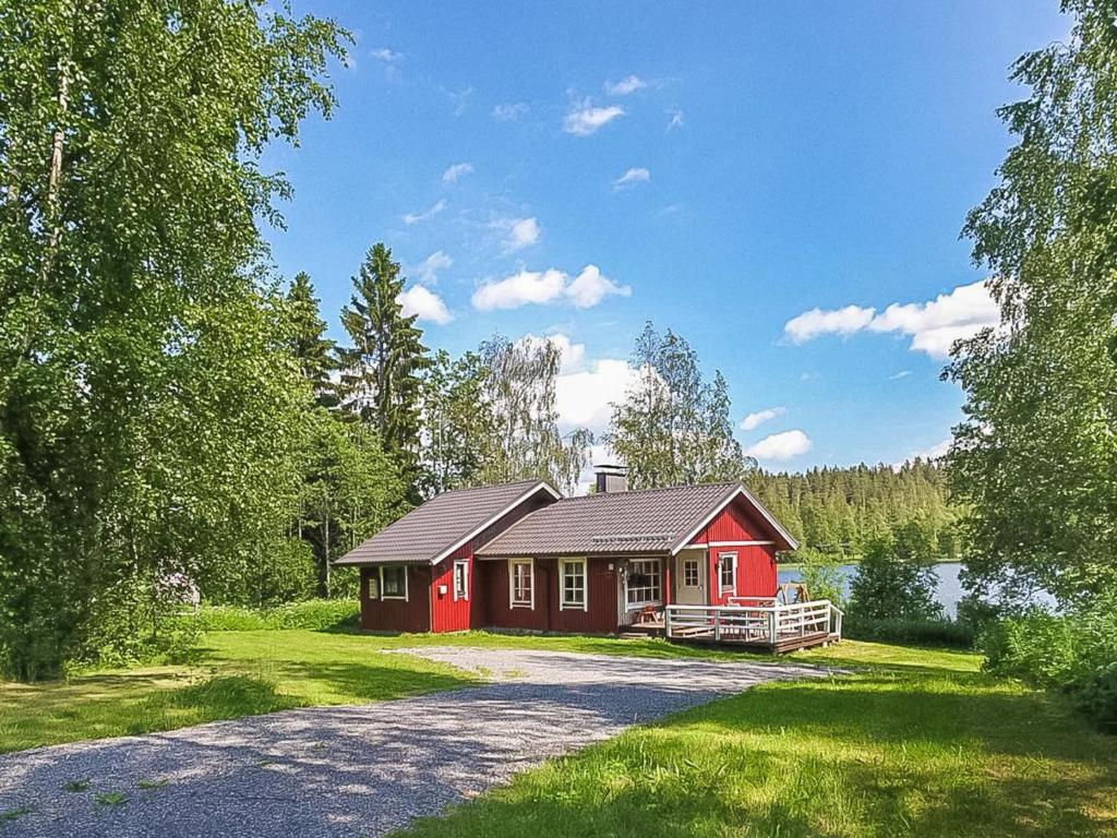 a small red house with a driveway next to a lake at Holiday Home Pajaranta by Interhome in Hara