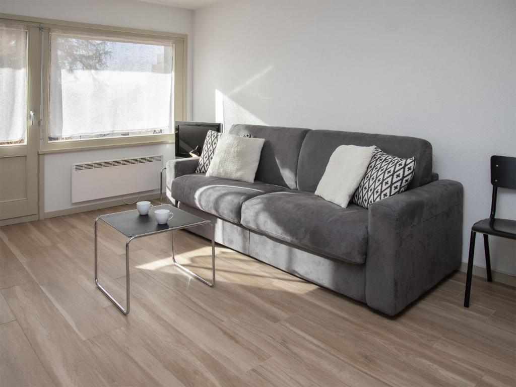 a living room with a gray couch and a table at Studio Diure 0113 by Interhome in Verbier