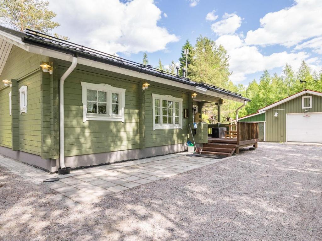 a green house with a porch and a driveway at Holiday Home Isoniemi by Interhome in Suinula