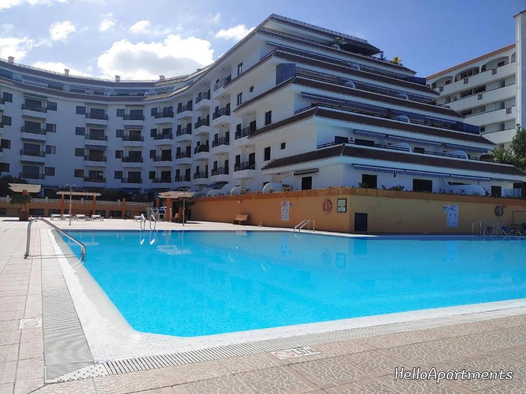 a swimming pool in front of a large building at Arena Sol by HelloApartments in Puerto de Santiago