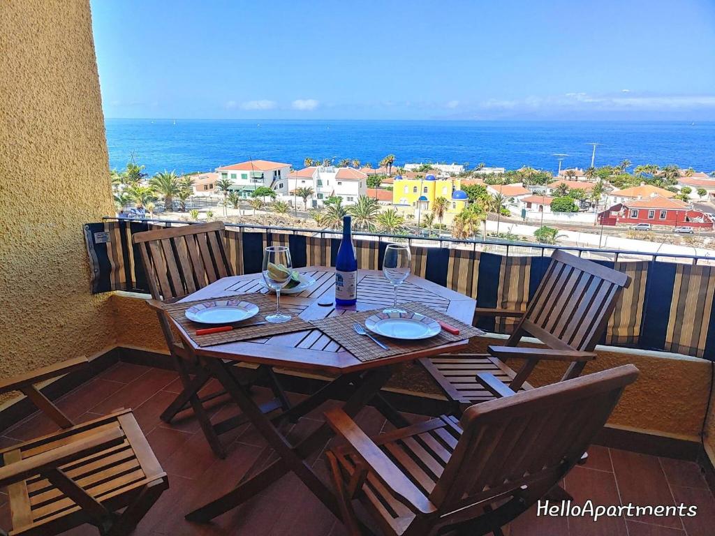 a table with chairs and wine glasses on a balcony at Sea View Playa Arena by HelloApartments in Puerto de Santiago
