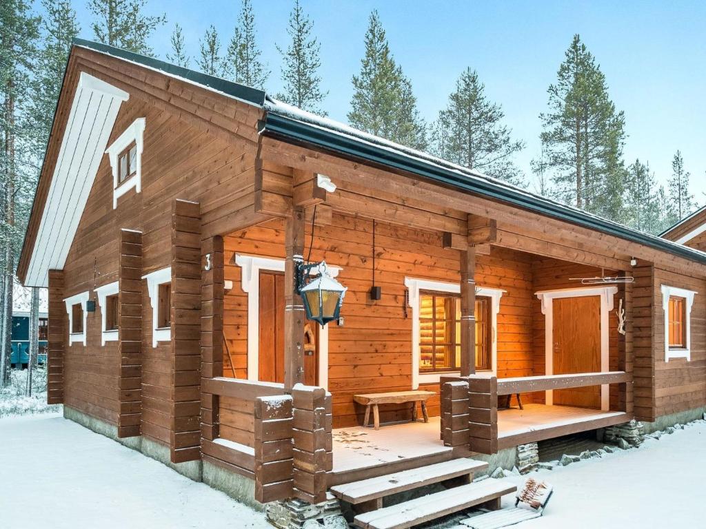 a log cabin with a porch in the snow at Holiday Home Honkakeko by Interhome in Levi
