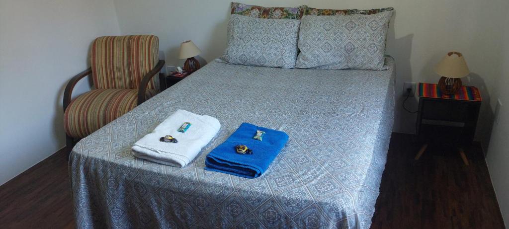 a bedroom with a bed with two towels and a chair at Quarto Suíte Amora in Atibaia