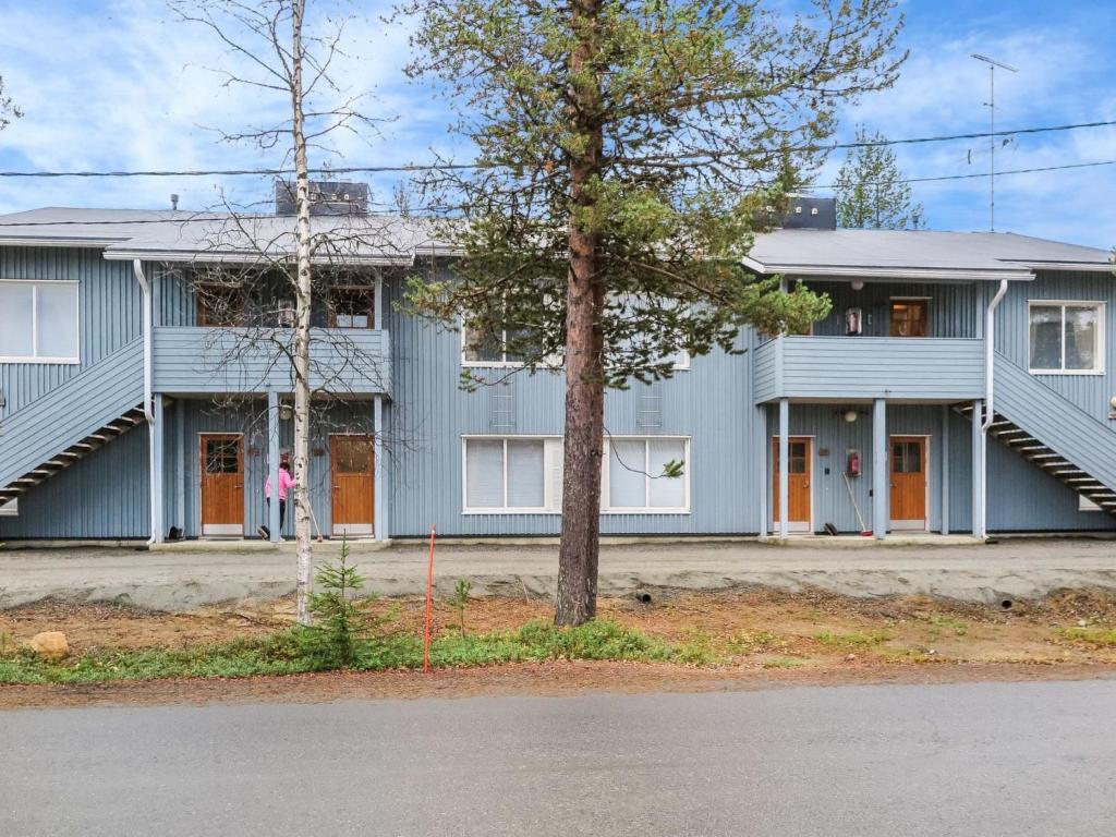 a blue house with a woman standing in front of it at Holiday Home Kanerva 202 by Interhome in Äkäslompolo