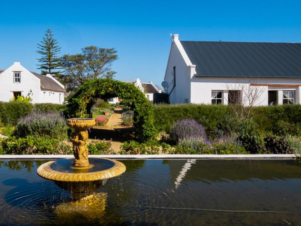 a yellow fountain in the middle of a pond in front of a house at Sempurna Estate in McGregor