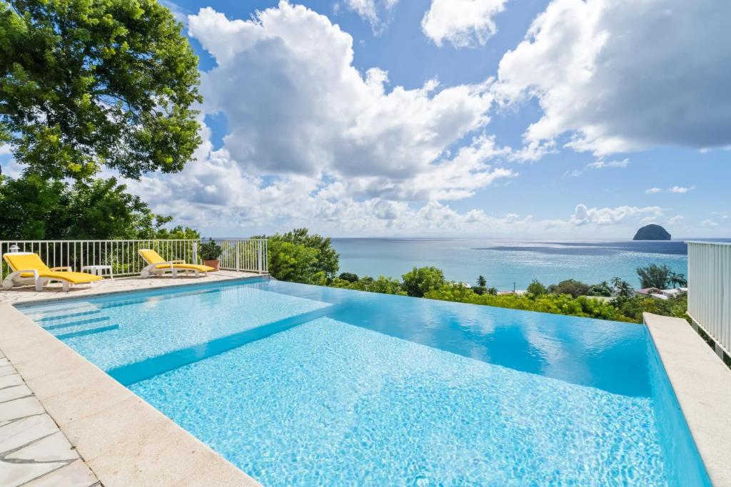 a swimming pool with a view of the ocean at Villa Lueurs du Rocher in Le Diamant