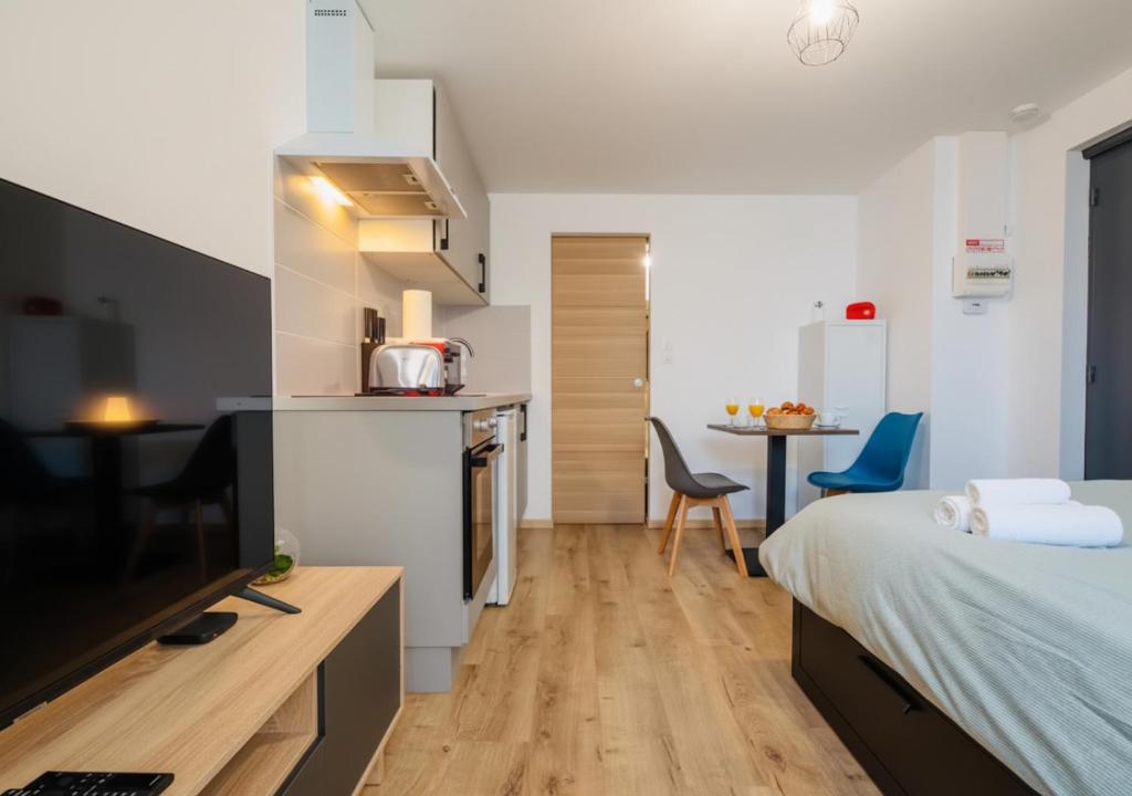 a bedroom with a bed and a kitchen with a table at Le Cocoon, studio centre, wifi, stationnement in Cognac
